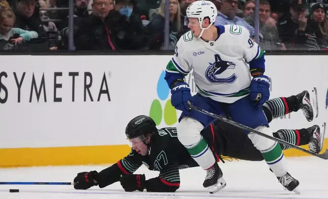 Seattle Kraken center Berkly Catton, left, falls against Vancouver Canucks center Marco Rossi, right, during the third period of an NHL hockey game Monday, Dec. 29, 2025, in Seattle. (AP Photo/Lindsey Wasson)