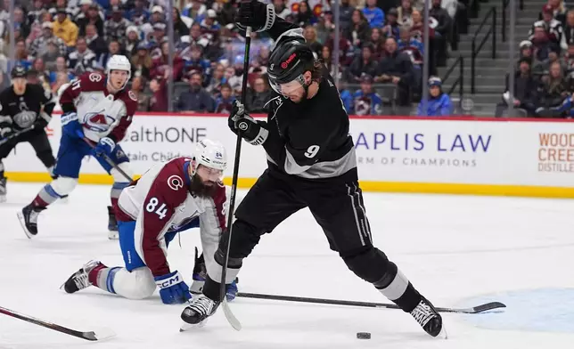 Los Angeles Kings right wing Adrian Kempe, front, redirects the puck as Colorado Avalanche defenseman Brent Burns covers in the second period of an NHL hockey game Monday, Dec. 29, 2025, in Denver. (AP Photo/David Zalubowski)