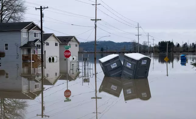 Partially inundated residences and portable toilets sit in floodwaters in Snohomish, Wash., Thursday, Dec. 11, 2025. (AP Photo/Stephen Brashear)