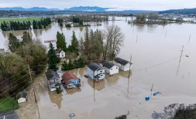 An aerial view shows homes surrounded by floodwaters in Snohomish, Wash., Thursday, Dec. 11, 2025. (AP Photo/Stephen Brashear)