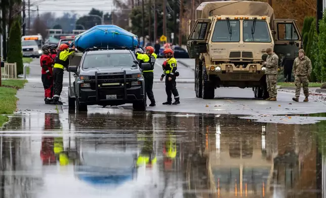 Emergency crews, including National Guard soldiers, wort in a neighborhood flooded by the Skagit River on Friday, Dec. 12, 2025, in Burlington, Wash. (AP Photo/Stephen Brashear)