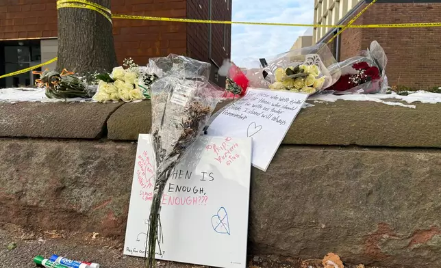 A memorial of flowers and signs lay outside the Barus and Holley engineering building at Brown University, on Hope Street in Providence, R.I., on Tuesday, Dec 16, 2025. (AP Photo/Matt OBrien)