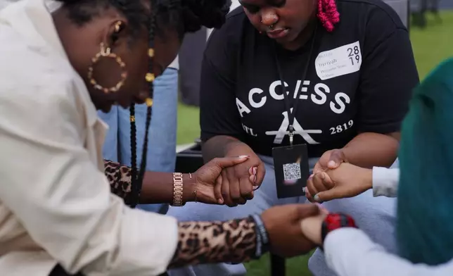 Nyriyah Hullman, center, and Brooklyn Marshall, right, hold hands to pray with fellow members of 2819 Church on Nov. 16, 2025, in Atlanta. (AP Photo/Jessie Wardarski)