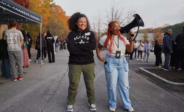 Brandi Porter, left, and Kennedy Onley, right, engage in a call and response with churchgoers as they wait in line on Nov. 16, 2025, in Atlanta. (AP Photo/Jessie Wardarski)
