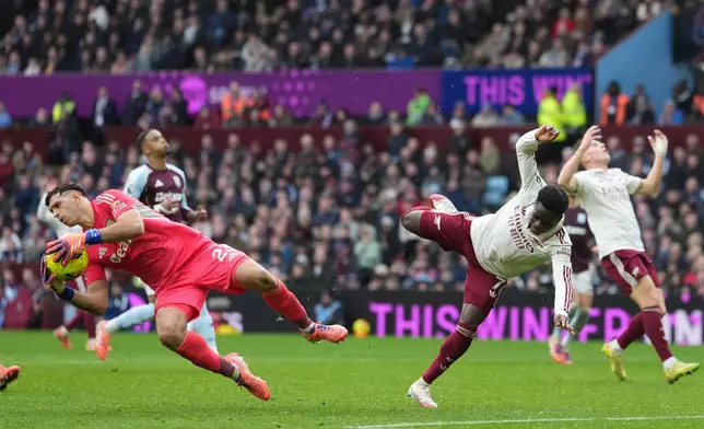 Aston Villa's goalkeeper Emiliano Martinez, left, makes a save ahead of Arsenal's Bukayo Saka during the English Premier League soccer match between Aston Villa and Arsenal in Birmingham, England, Saturday, Dec. 6, 2025. (AP Photo/Dave Shopland)