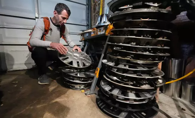 Cyclist Barnaby Wickham sorts through his collection of hubcaps stored in his garage, Thursday, Dec. 11, 2025, at his home in Baltimore. (AP Photo/Stephanie Scarbrough)
