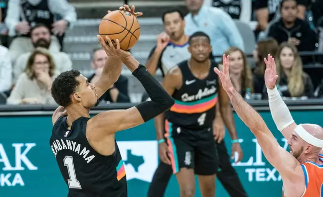 San Antonio Spurs forward Victor Wembanyama (1) hits a three point shot over Oklahoma Thunder guard Alex Caruso (9) during the second half of an NBA basketball game in San Antonio, Tuesday, Dec. 23, 2025. (AP Photo/Rodolfo Gonzalez)