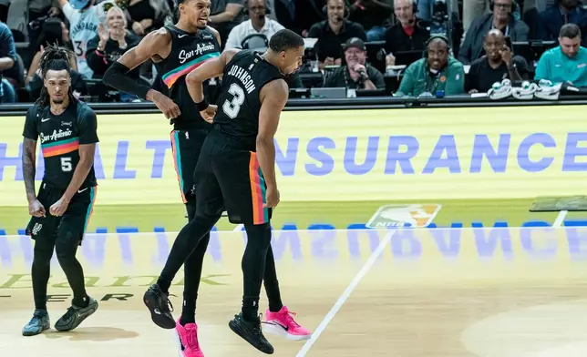 San Antonio Spurs forward Victor Wembanyama (1) and San Antonio Spurs forward Keldon Johnson (3) celebrate Johnson's basket against the Oklahoma Thunder during the second half of an NBA basketball game in San Antonio, Tuesday, Dec. 23, 2025. (AP Photo/Rodolfo Gonzalez)