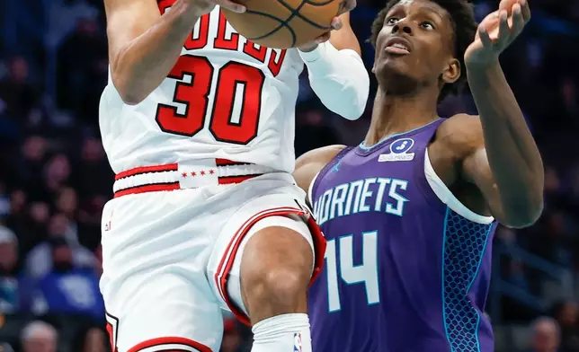 Chicago Bulls guard Tre Jones (30) drives to the basket against Charlotte Hornets forward Moussa Diabate (14) during the first half of an NBA basketball game in Charlotte, N.C., Friday, Dec. 12, 2025. (AP Photo/Nell Redmond)