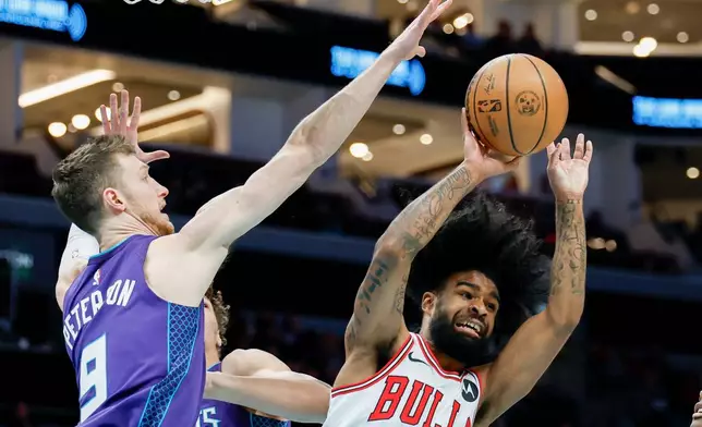 Chicago Bulls guard Coby White, right, looks to pass the ball against Charlotte Hornets forward Drew Peterson, left, during the first half of an NBA basketball game in Charlotte, N.C., Friday, Dec. 12, 2025. (AP Photo/Nell Redmond)
