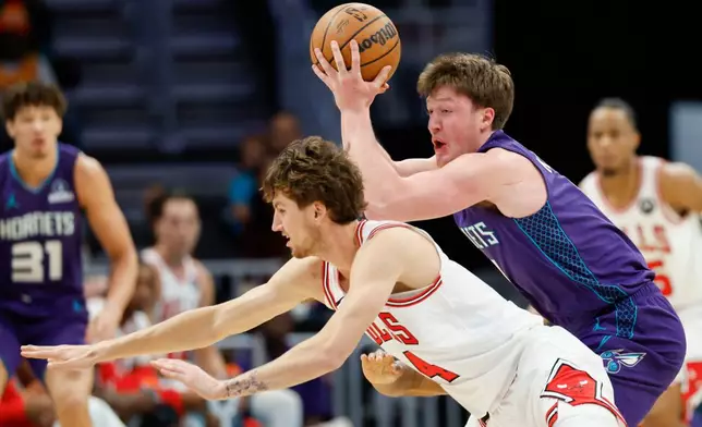 Charlotte Hornets guard Kon Knueppel, right, controls the ball against Chicago Bulls forward Matas Buzelis, left, during the first half of an NBA basketball game in Charlotte, N.C., Friday, Dec. 12, 2025. (AP Photo/Nell Redmond)