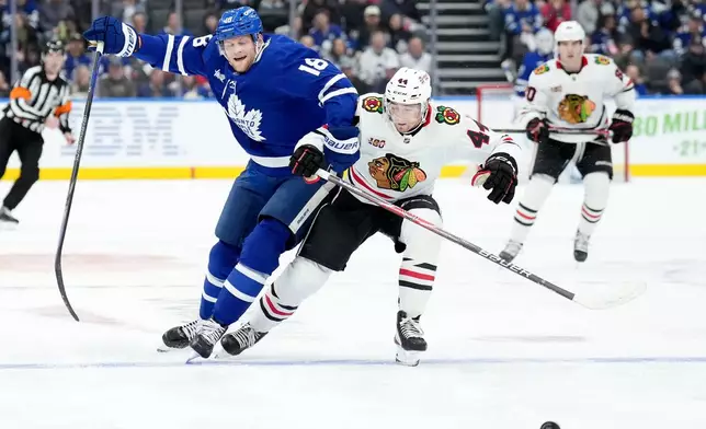 Toronto Maple Leafs forward Steven Lorentz (18) and Chicago Blackhawks defenceman Wyatt Kaiser (44) vie for control of the puck during the second period of an NHL hockey game in Toronto, Tuesday, Dec. 16, 2025. (Nathan Denette/The Canadian Press via AP)