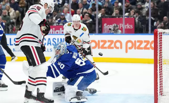 Chicago Blackhawks forward Dominic Toninato (25) scores past Toronto Maple Leafs goaltender Joseph Woll (60) during first period NHL hockey action in Toronto, Tuesday, Dec. 16, 2025. (Nathan Denette/The Canadian Press via AP)