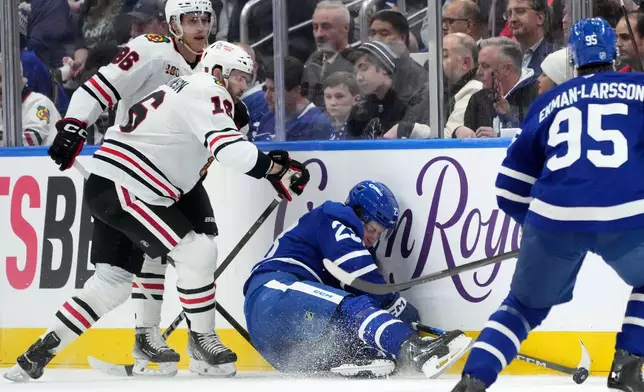 Chicago Blackhawks forward Jason Dickinson (16) checks Toronto Maple Leafs forward Matthew Knies (23) during the first period of an NHL hockey game in Toronto, Tuesday, Dec. 16, 2025. (Nathan Denette/The Canadian Press via AP)