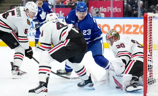 Chicago Blackhawks goaltender Spencer Knight (30) makes a save on Toronto Maple Leafs forward Matthew Knies (23) during second period NHL hockey action in Toronto, Tuesday, Dec. 16, 2025. (Nathan Denette/The Canadian Press via AP)