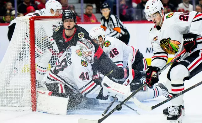 Chicago Blackhawks goalie Arvid Soderblom (40) tracks the puck as Ottawa Senators' Tim Stutzle (18) crashes into the net during second-period NHL hockey game action in Ottawa, Ontario, Saturday, Dec. 20, 2025. (Spencer Colby/The Canadian Press via AP)