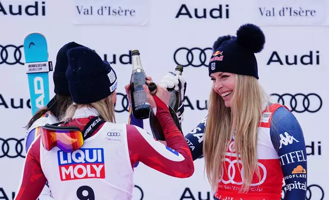 Austria's Cornelia Huetter, left, winner of an alpine ski, women's World Cup downhill, celebrates on the podium with second-placed Germany's Kira Weidle Winkelmann, left, and third-placed United States' Lindsey Vonn, in Val D'Isere, France, Saturday, Dec. 20, 2025. (AP Photo/Pier Marco Tacca)