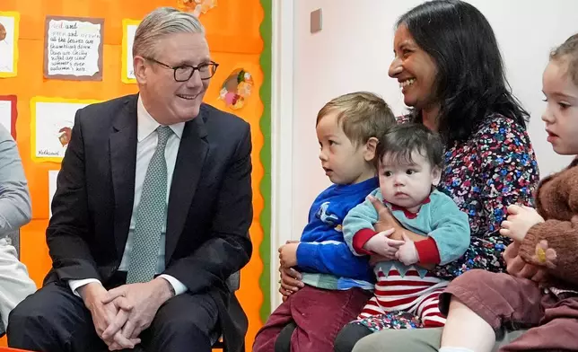 Britain's Prime Minister Keir Starmer, left, speaks with parents and children during his visit to a nursery, in central London, Monday, Dec. 1, 2025. (Gareth Fuller/Pool Photo via AP)