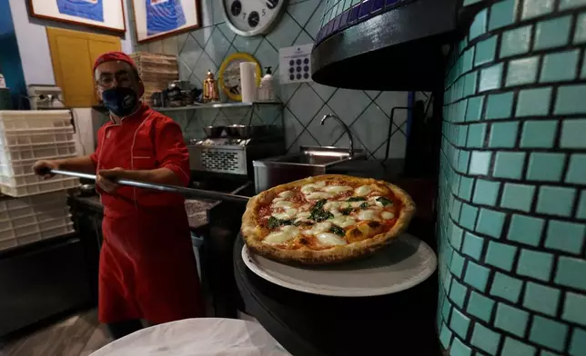 FILE -Eugenio Iorio bakes a pizza at a restaurant in Naples, Italy, Saturday, Nov. 14, 2020. (AP Photo/Gregorio Borgia, File)