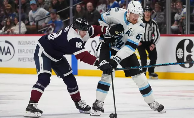 Colorado Avalanche center Jack Drury, left, battles for control of the puck with Utah Mammoth left wing Lawson Crouse in the second period of an NHL hockey game Tuesday, Dec. 23, 2025, in Denver. (AP Photo/David Zalubowski)