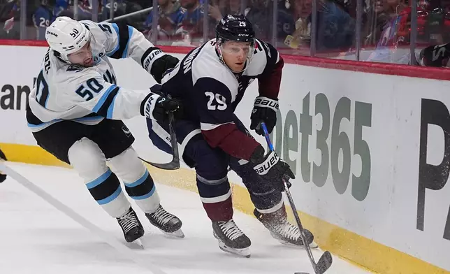 Colorado Avalanche center Nathan MacKinnon, right, drives past Utah Mammoth defenseman Sean Durzi in the first period of an NHL hockey game Tuesday, Dec. 23, 2025, in Denver. (AP Photo/David Zalubowski)