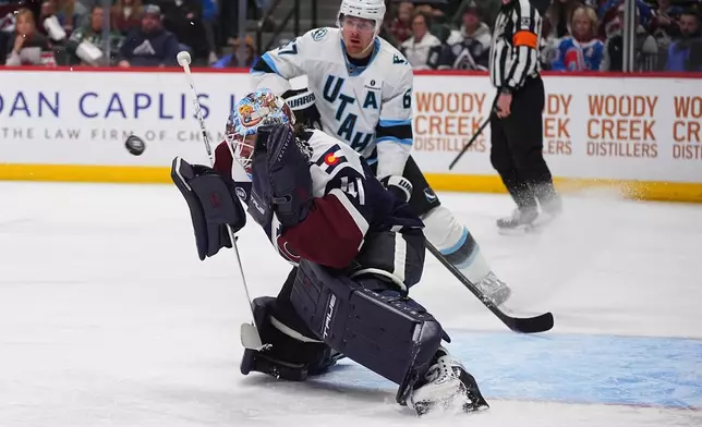 Colorado Avalanche goaltender Scott Wedgewood, front, deflects a shot as Utah Mammoth left wing Lawson Crouse looks on in the second period of an NHL hockey game Tuesday, Dec. 23, 2025, in Denver. (AP Photo/David Zalubowski)