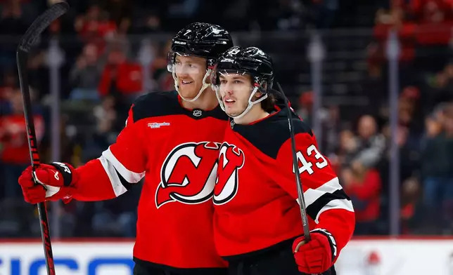 New Jersey Devils defenseman Luke Hughes (43) celebrates with Dougie Hamilton, left, after scoring against the Vancouver Canucks during the second period of an NHL hockey game, Sunday, Dec 14, 2025, in Newark, N.J. (AP Photo/Noah K. Murray)