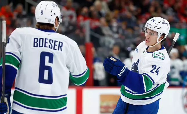 Vancouver Canucks defenseman Zeev Buium (24) celebrates with right wing Brock Boeser (6) after scoring a goal against the New Jersey Devils during the first period of an NHL hockey game, Sunday, Dec 14, 2025, in Newark, N.J. (AP Photo/Noah K. Murray)