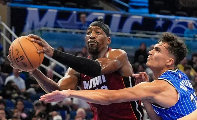 Miami Heat center Bam Adebayo, left, grabs a rebound away from Orlando Magic forward Tristan da Silva during the second half of an NBA basketball game, Friday, Dec. 5, 2025, in Orlando, Fla. (AP Photo/John Raoux)