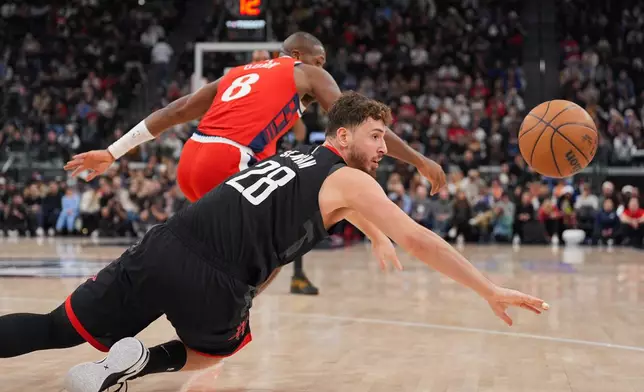 Houston Rockets center Alperen Sengun (28) reaches for a loose ball as Los Angeles Clippers guard Kris Dunn (8) watches during the first half of an NBA basketball game Tuesday, Dec. 23, 2025, in Inglewood, Calif. (AP Photo/Jae C. Hong)