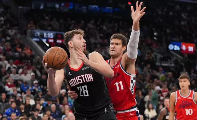 Houston Rockets center Alperen Sengun (28) looks to pass under defense by Los Angeles Clippers center Brook Lopez (11) during the first half of an NBA basketball game Tuesday, Dec. 23, 2025, in Inglewood, Calif. (AP Photo/Jae C. Hong)