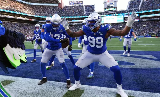 REMOVES ZACH CHARBONNET - Seattle Seahawks linebacker Ernest Jones IV (13) and defensive end Leonard Williams (99) celebrate after an interception by Jones during the second half of an NFL football game against the Minnesota Vikings on Sunday, Nov. 30, 2025, in Seattle. (AP Photo/ Lindsey Wasson)