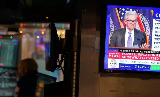A television on the floor at the New York Stock Exchange in New York, display a news conference with Fed chairman Jerome Powell, Wednesday, Dec. 10, 2025. (AP Photo/Seth Wenig)