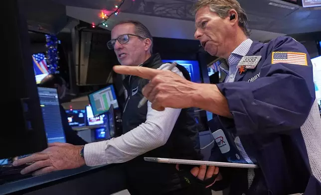 Specialist Glenn Carell, left, and trader Robert Charmak work on the floor of the New York Stock Exchange, Thursday, Dec. 11, 2025. (AP Photo/Richard Drew)