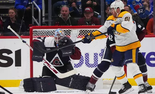 Nashville Predators center Jonathan Marchessault, front right, redirects the puck at Colorado Avalanche goaltender Scott Wedgewood, left, while battling for position with defenseman Josh Manson in the first period of an NHL hockey game Saturday, Dec. 13, 2025, in Denver. (AP Photo/David Zalubowski)