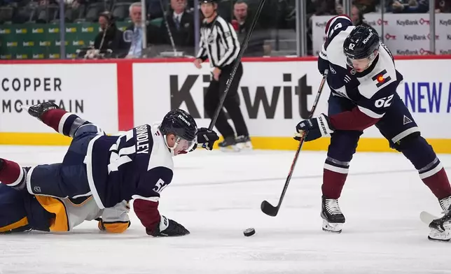 Colorado Avalanche left wing Artturi Lehkonen, right, collects the puck as Colorado Avalanche center Gavin Brindley, top left, falls on Nashville Predators defenseman Roman Josi in the first period of an NHL hockey game, Saturday, Dec. 13, 2025, in Denver. (AP Photo/David Zalubowski)