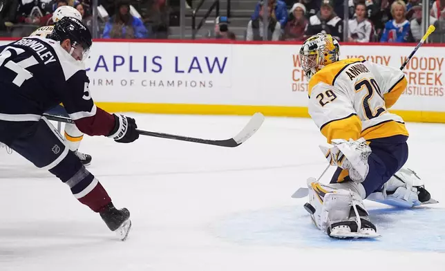 Colorado Avalanche center Gavin Brindley, left, has his shot deflected off the pad of Nashville Predators goaltender Justus Annunen in the first period of an NHL hockey game, Saturday, Dec. 13, 2025, in Denver. (AP Photo/David Zalubowski)