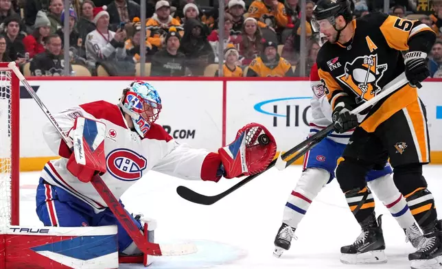 Montréal Canadiens goaltender Jakub Dobes, left, gloves a shot with Pittsburgh Penguins' Kris Letang, right, looking for a rebound and Cole Caufield, rear right, defending during the second period of an NHL hockey game in Pittsburgh, Sunday, Dec. 21, 2025. (AP Photo/Gene J. Puskar)