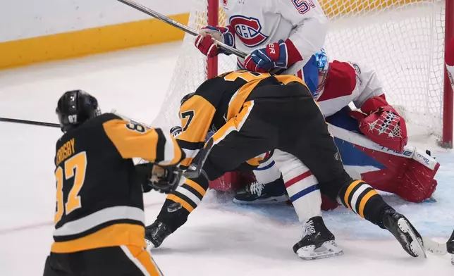 Pittsburgh Penguins' Sidney Crosby (87) shoots through traffic for a goal which tied him with former Penguins player Mario Lemieux for the team's all-time points leader during the first period of an NHL hockey game against the Montréal Canadiens in Pittsburgh, Sunday, Dec. 21, 2025. (AP Photo/Gene J. Puskar)