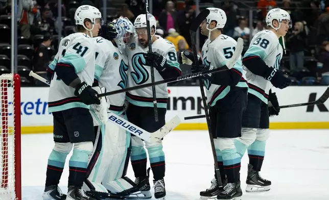 Seattle Kraken players celebrate the team's win over the Anaheim Ducks in an NHL hockey game, Monday, Dec. 22, 2025, in Anaheim, Calif. (AP Photo/Kyusung Gong)