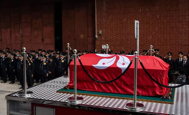A hearse carries Ho Wai-ho, the firefighter who lost his life in the line of duty during the deadly fire at Wang Fuk Court on Nov. 26, as it passes by a funeral parlor, in Hong Kong, Friday, Dec. 19, 2025. (AP Photo/Chan Long Hei)