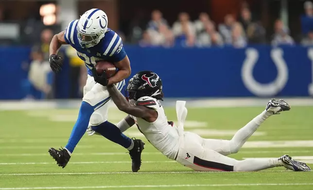 Indianapolis Colts running back Jonathan Taylor (28) is tackled by Houston Texans safety Calen Bullock (2) during the second half of an NFL football game Sunday, Nov. 30, 2025, in Indianapolis. (AP Photo/Michael Conroy)