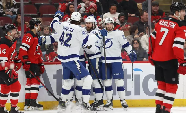 From left, Tampa Bay Lightning's Curtis Douglas (42), Nick Paul (20), Scott Sabourin (46) and Max Crozier (24) react after Paul scored against the New Jersey Devils during the first period of an NHL hockey game Thursday, Dec. 11, 2025, in Newark, N.J. (AP Photo/Pamela Smith)