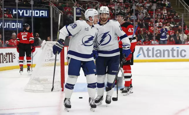 Tampa Bay Lightning's Jake Guentzel (59) reacts with Oliver Bjorkstrand (22) after scoring a goal against the New Jersey Devils during the first period of an NHL hockey game Thursday, Dec. 11, 2025, in Newark, N.J. (AP Photo/Pamela Smith)