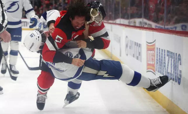 New Jersey Devils' Brenden Dillon (5) fights with Tampa Bay Lightning's Scott Sabourin (46) during the first period of an NHL hockey game Thursday, Dec. 11, 2025, in Newark, N.J. (AP Photo/Pamela Smith)