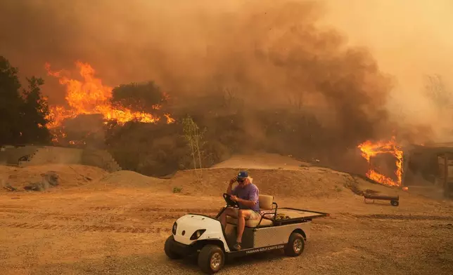 FILE - A resident rides a golf cart as he exits his property while the Canyon Fire burns on Aug. 7, 2025, in Hasley Canyon, Calif. (AP Photo/Marcio Jose Sanchez, File)