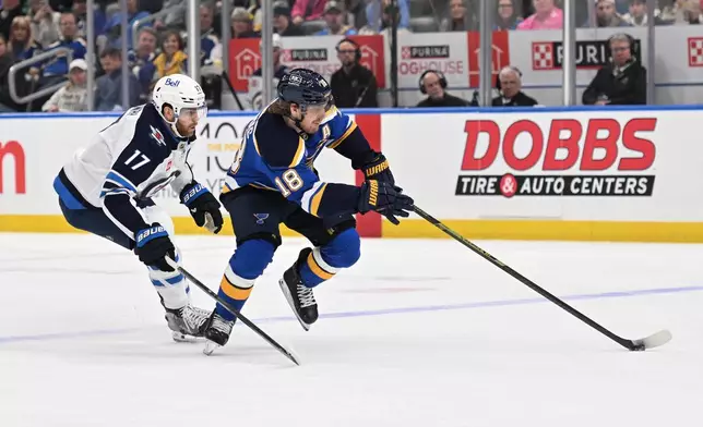 Winnipeg Jets center Adam Lowry (17), left, pressures St. Louis Blues center Robert Thomas (18) during the second period of an NHL hockey game on Wednesday, Dec. 17, 2025, in St. Louis. (AP Photo/Joe Puetz)