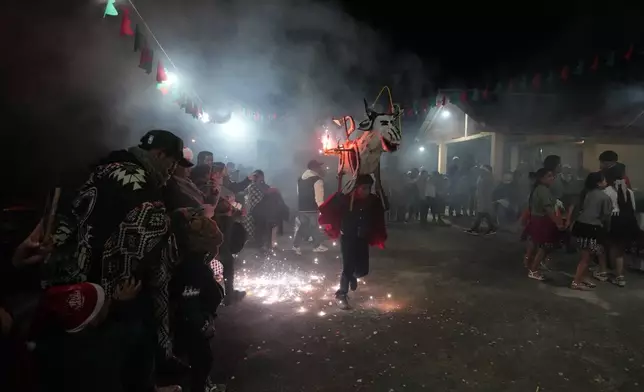 A child runs with a traditional vaca loca, or crazy cow, during Christmas celebrations in Quingeo, Ecuador, Tuesday, Dec. 23, 2025. (AP Photo/Dolores Ochoa)