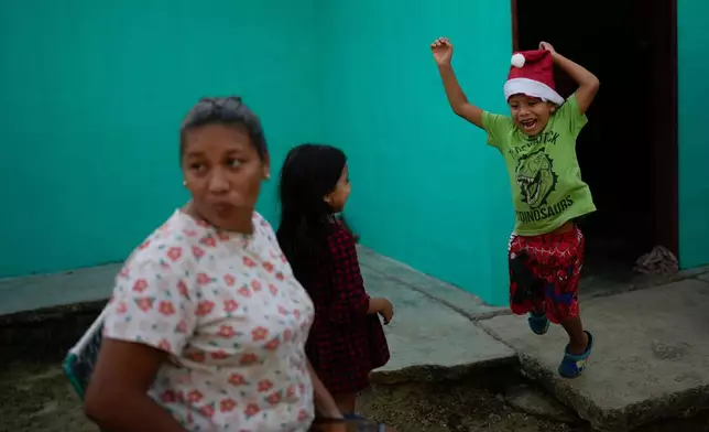 Mathias jumps after receiving a Christmas present from his mother, Mariela Gómez, left, in Maracay, Venezuela, Wednesday, Dec. 24, 2025. The two returned home after abandoning their journey to the United States following President Donald Trump's immigration crackdown. (AP Photo/Matias Delacroix)