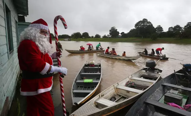 A man dressed as Santa Claus arrives to distribute Christmas gifts to children living in riverside communities in Careiro da Varzea, Brazil, Saturday, Dec. 20, 2025. (AP Photo/Edmar Barros)